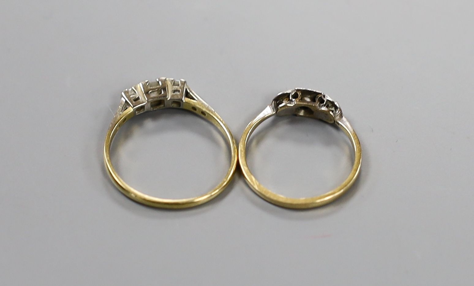 Two early 20th century yellow metal (one stamped 18ct & plat) and three stone diamond rings, one with diamond set shoulders, sizes N & Q, gross weight 4.1 grams.